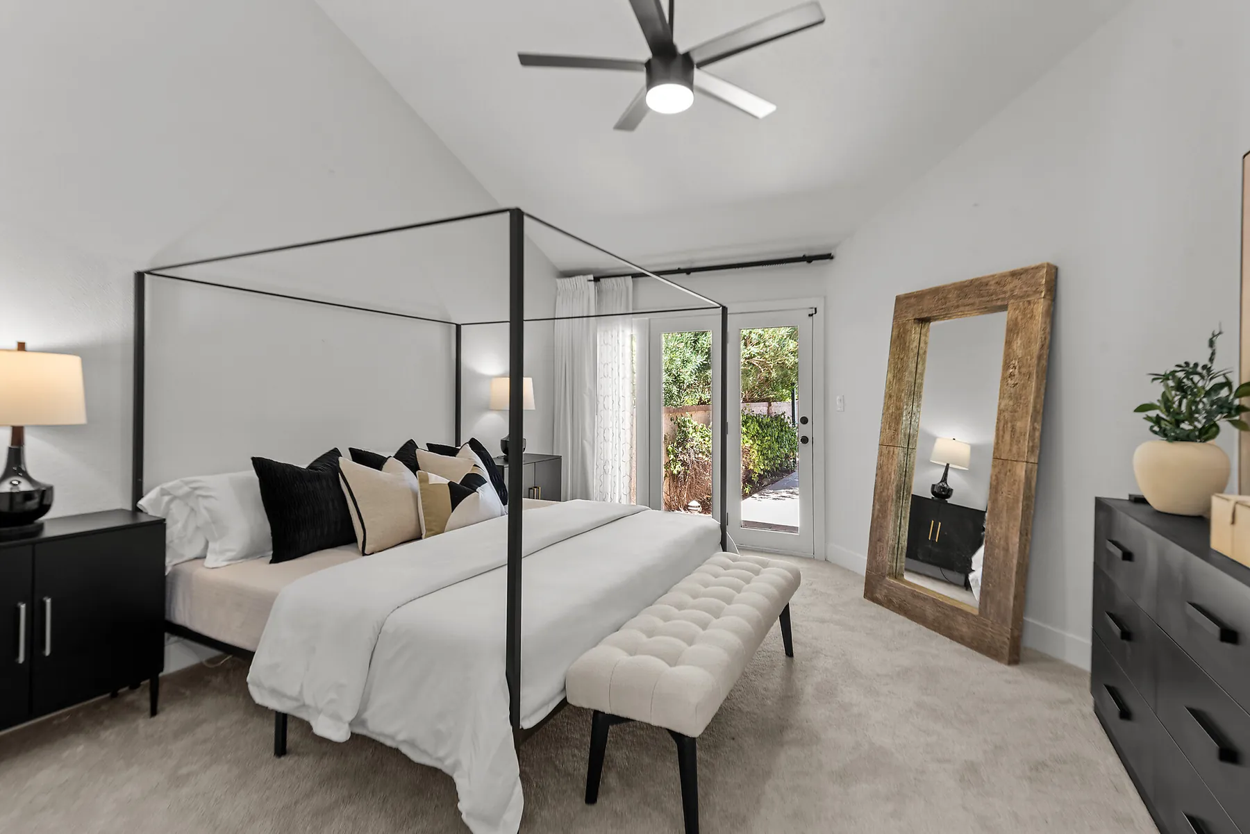A staged primary bedroom with a black canopy bed